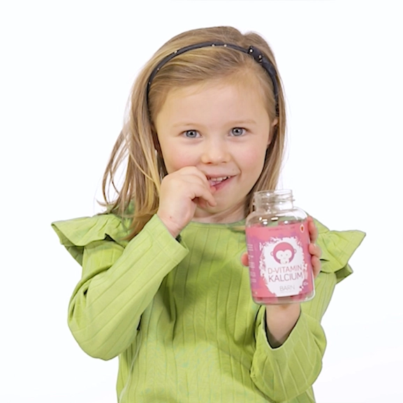 Barn håller i burk innehållande Monkids™ D-vitamin + Kalcium Barn Jordgubb.